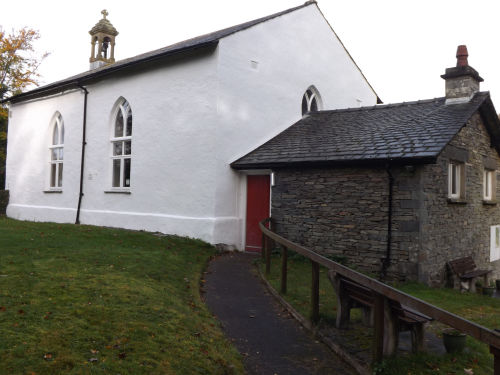 The whitewashed Braithwaite Hall with its slate outbuilding and lawn